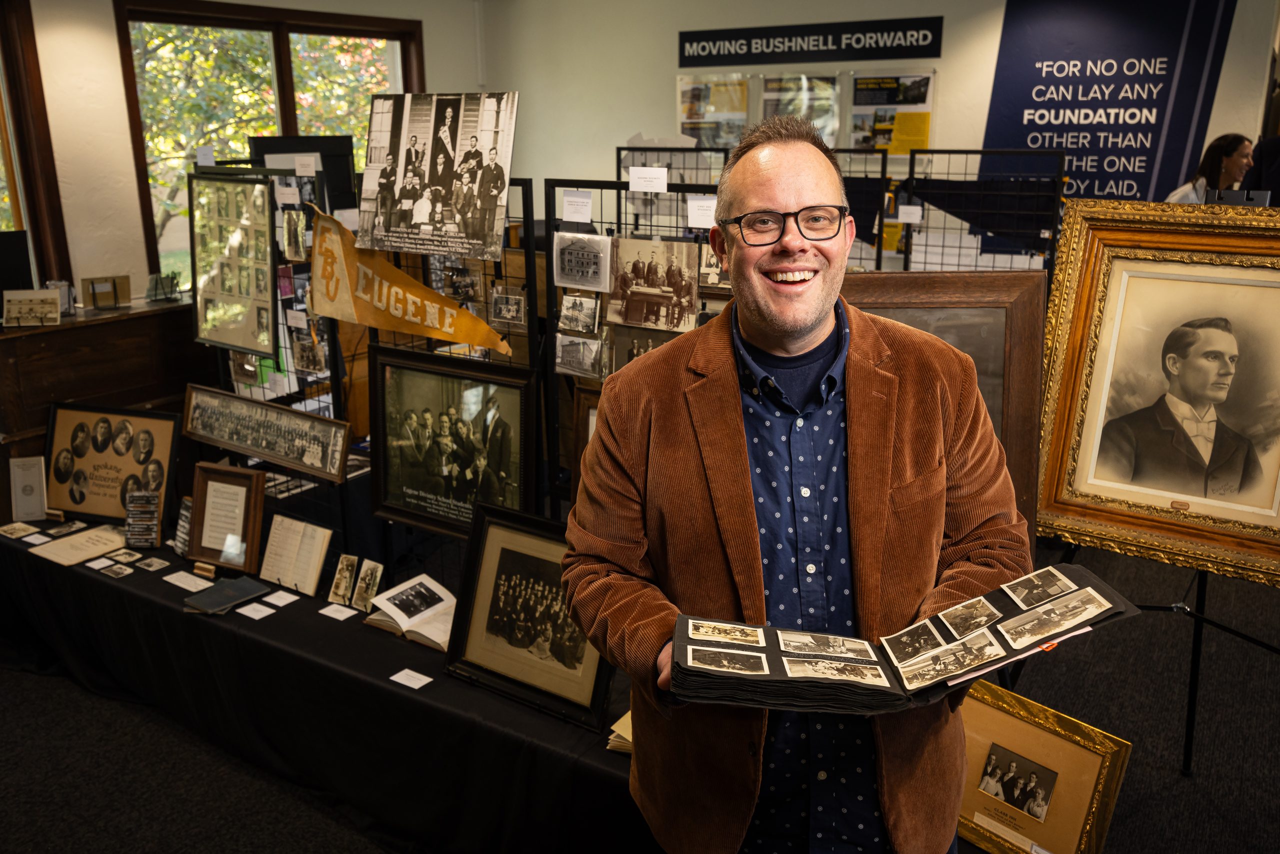 Stephen Andes holding a historical photo album at a Bushnell history exhibit