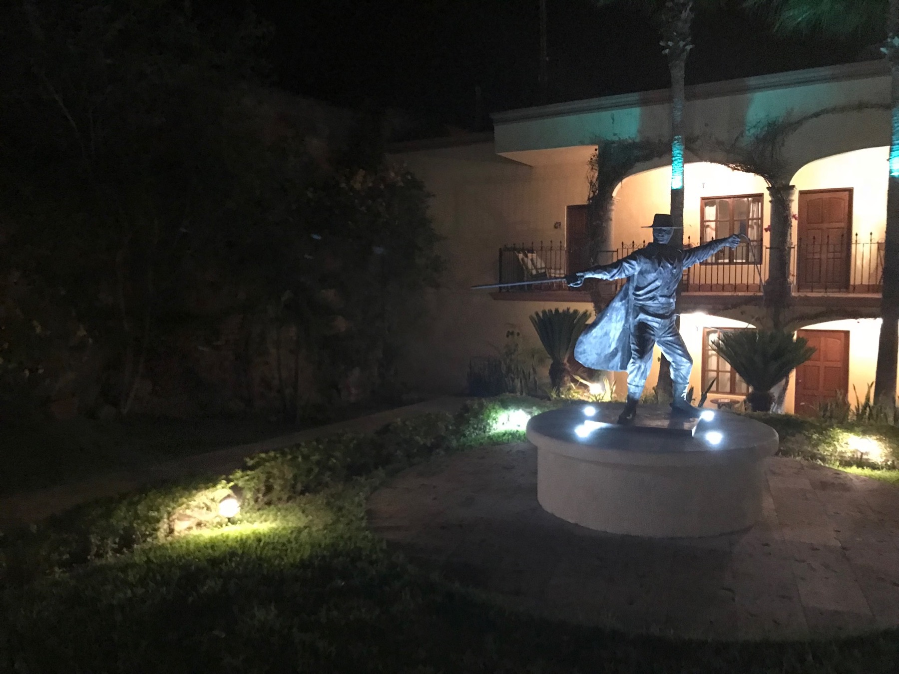 An illuminated statue of Zorro in the Posada del Hidalgo courtyard at night